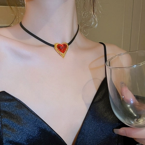 Close-up of a vintage red heart pendant choker with golden textured edges on a model