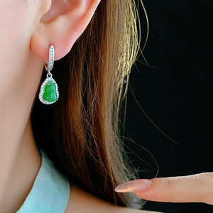 Detail of zircon gourd earring in silver finish with green jade on model's ear