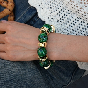 Detailed close-up of green marbled beads and polished irregular gold metal links on a bracelet