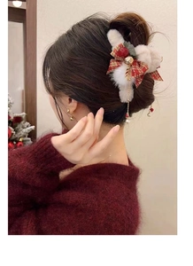 Christmas plush hair claw clip with golden tassels and red bow on model's head