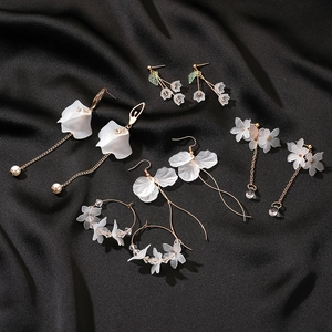 Elegant floral tassel earrings with white resin petals and gold accents on black silk