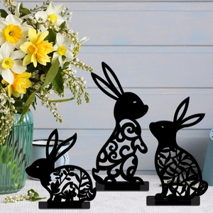 Three black cutout bunny table decorations with floral patterns on white surface