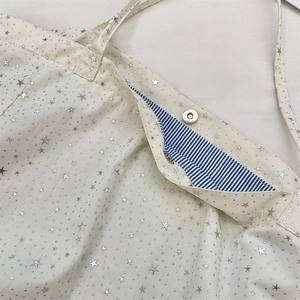 Close-up of beige canvas tote with silver star prints and magnetic metal clasp