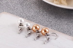 Détail macro des boucles d'oreilles à clips perles blanches et champagne sur bois