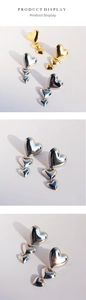 Détail de boucles d'oreilles pendantes triple cœur en métal poli doré et argenté