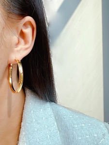 Polished gold large hoop earring worn by a model showcasing minimalist style and scale