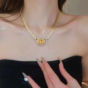 Detail of vintage gold necklace with large yellow oval gemstone and sparkling zircon accents