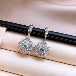 Macro view of crystal flower earrings with a green center stone and silver plating