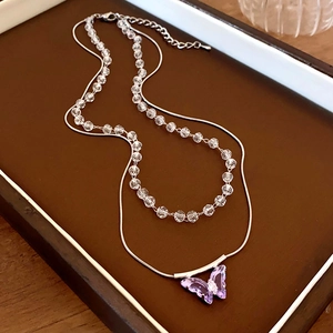 Detail of double-layer necklace with purple crystal butterfly and beaded snake chain