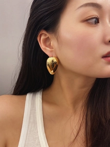 Close-up of high-polish gold teardrop earrings worn by a model for a fashion look
