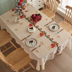 Detailed embroidery of red bows and pine wreaths on a beige Christmas tablecloth
