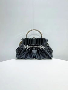 Detail of black pleated evening clutch with rhinestone flowers and silver ring handle