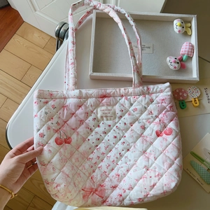 Nahaufnahme der gesteppten Baumwolltasche mit Kirschmuster auf einem weißen Tisch