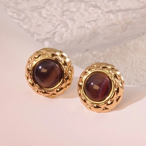 Close-up of vintage gold button earrings with purple stone and quilted texture detail