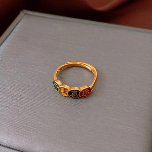 Vue détaillée d'une bague dorée avec breloques en émail et gravure 999 sur l'anneau