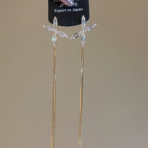 Détail de boucles d'oreilles dorées à pampilles avec zircons en forme d'étoile