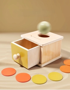 Detail of wooden Montessori object permanence box with coin slot and colorful discs