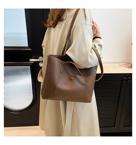 Dettaglio della borsa tote in pelle marrone con tasca esterna cucita e bottone a scatto
