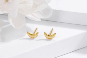 Close-up of polished S925 sterling silver crescent moon stud earrings in gold finish