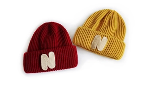 Close-up of red and yellow ribbed knit beanies featuring white N-letter embroidered patches