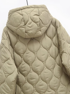 Close-up of wavy quilting and hooded design on khaki long warm hooded cotton coat