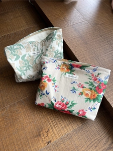Makro-Detail von Vintage-Baumwoll-Kosmetiktaschen mit Blumenmuster auf Holzstufen
