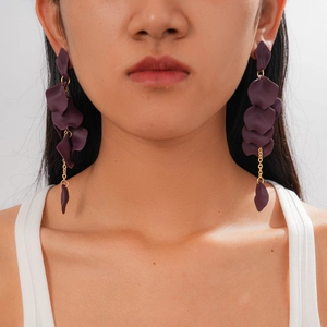 Detailed close-up of dark purple acrylic petal tassel earrings worn by a model