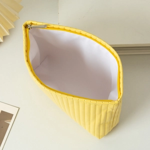 Macro view showing large internal storage space and silver zipper of yellow quilted bag