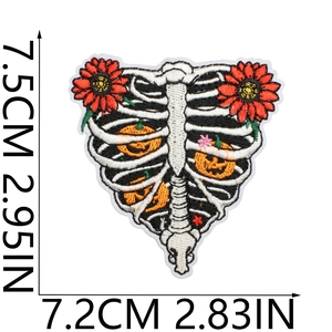 Detailed embroidery view of a skeleton ribcage patch with pumpkins and red flowers