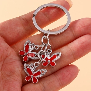 Close-up of three red enamel butterfly charms with sparkling rhinestones on silver keychain