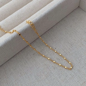 Detailed close-up of S925 silver gold bracelet with small cube beads on woven jewelry box