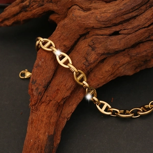 Detailed shot of golden pig nose link chain bracelet on a rustic wood texture