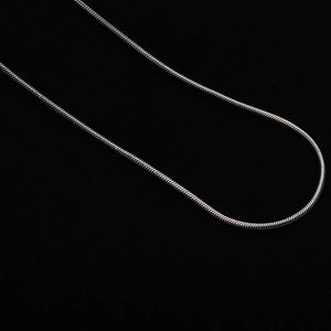 Close-up of a 1mm silver-plated snake chain necklace on a minimalist black background