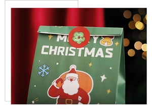 Close-up of green Christmas paper gift bag with Santa Claus pattern and golden bell details