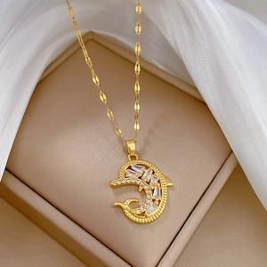 Golden dolphin pendant necklace with clear zircon stones on a white silk background