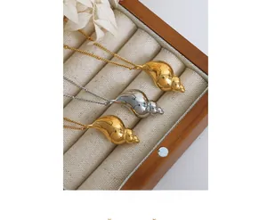 Detail of gold and silver conch shell pendants on linen inside a wooden jewelry box