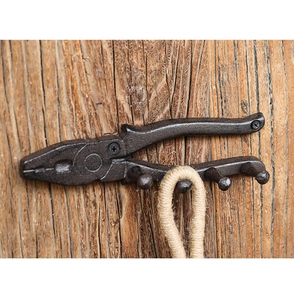 Close-up of vintage cast iron pliers wall hook with 4 pegs on rustic wood background