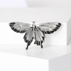 Detail of vintage silver butterfly brooch with black enamel inlay on geometric stand