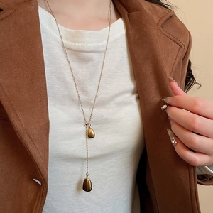 Detail view of a long 18k gold plated Y-necklace with two teardrop pendants on a model