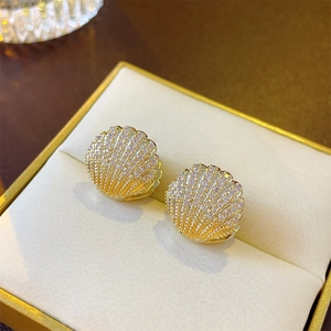 Detailed view of gold-plated shell earrings with micro-set zircons on velvet box