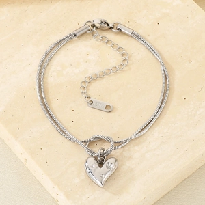 Detail of silver heart pendant and knot element on double-layer pearl snake chain