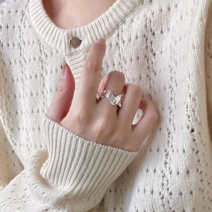 Detail of irregular textured 925 sterling silver ring worn on model with knitted background