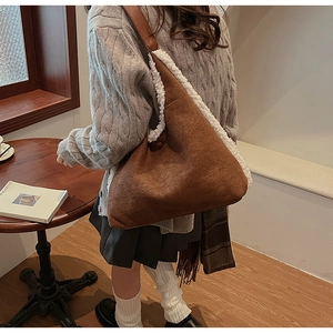 Brown suede shoulder bag featuring soft white faux fur trim and unique triangular design