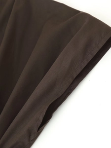 Macro detail showing woven cotton-linen fabric texture and neat stitching on coffee brown dress