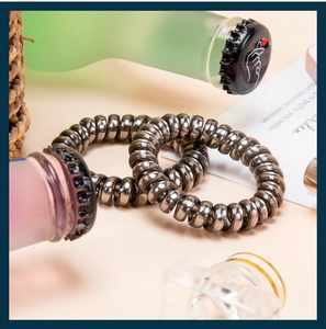 Macro detail of metallic gunmetal spiral hair ties with flexible telephone wire texture