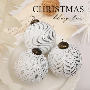 Detailed view of 8cm white Christmas ornaments with silver geometric patterns on a plate