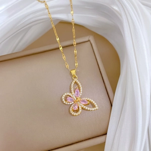 Macro shot of gold butterfly pendant with pink gemstones and crystals on beige box