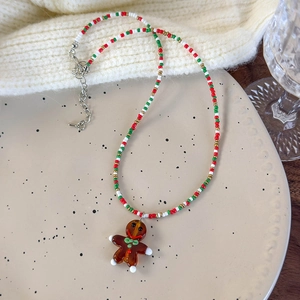Detailed shot of Christmas beaded necklace featuring a gingerbread man charm on ceramic