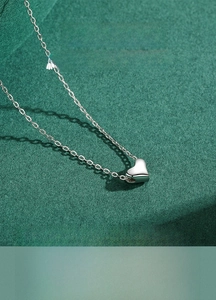 Detailed macro view of S925 sterling silver heart pendant necklace on textured green background