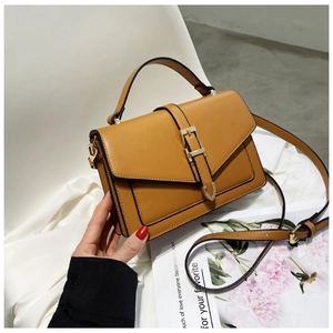 Close-up of brown PU leather bag with gold metal buckle on white silk background